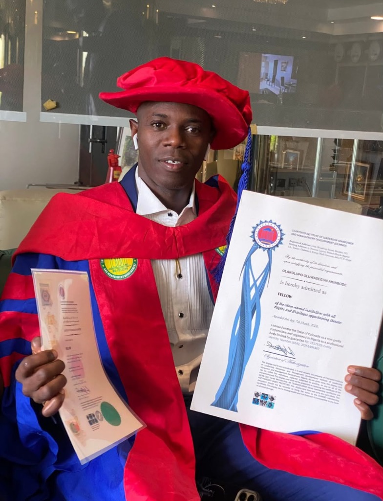 Akinbode Olakolupo Oluwasegun in academic regalia holding his Fellowship certificate from CILMMD